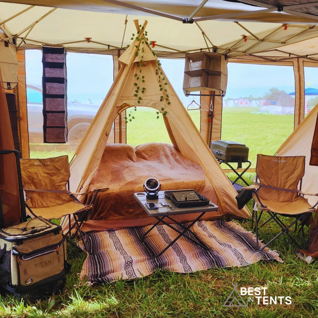Luxury festival tent interior with cozy bed, camping chairs, table, and Best in Tents logo